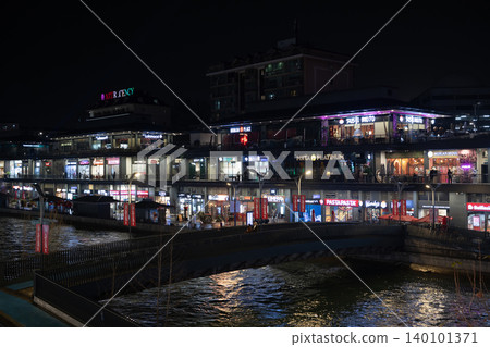 Tashkent, Uzbekistan - February 02, 2026: Seoul Mun Street. Rainy Evening with Neon Lights and People Walking. Tashkent, Uzbekistan - February 02, 2026: Seoul Mun Street. Rainy Evening with Neon Lights and People Walking. 140101371