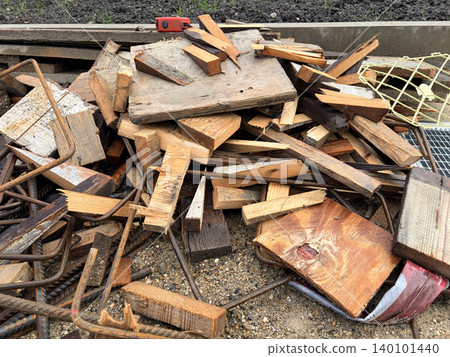 a chaotic pile of construction debris and waste resting on sandy, gravelly ground. A worksite 140101440