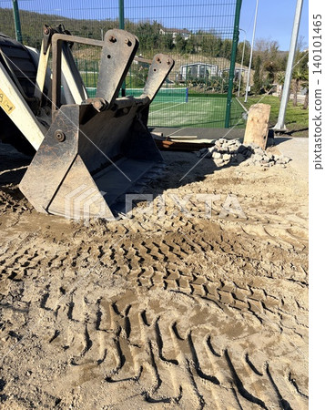 Outdoor construction site with metal bucket collecting soil 140101465
