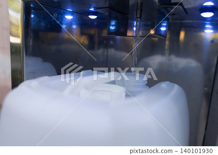 Filling a plastic canister with clean drinking water from an automatic vending machine. Close up of water pouring into a bottle. Filling a plastic canister with clean drinking water from an automatic vending machine. Close up of water pouring into a bottle. 140101930