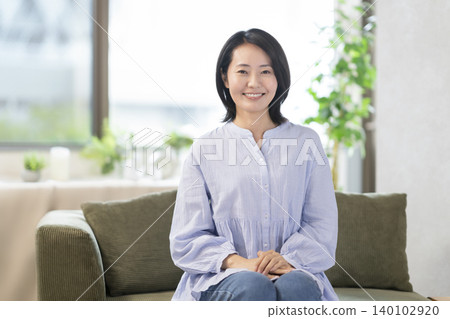 一位中年婦女看著鏡頭微笑 一位中年婦女看著鏡頭微笑 140102920