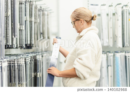 Woman selecting curtain rail in home improvement store department 140102988