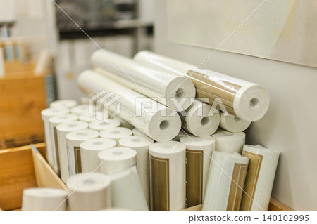 Stacked white wallpaper rolls and renovation materials displayed in hardware store interior 140102995