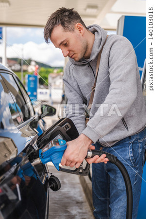 Young man filling black vehicle with gasoline at modern fuel station during everyday driving and transportation activity Young man filling black vehicle with gasoline at modern fuel station during everyday driving and transportation activity 140103018