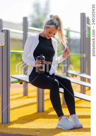 Athletic woman enjoying hydration during outdoor fitness training break 140103430