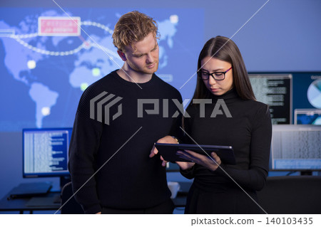 Young professionals analyzing cyber threats on a tablet in a SOC environment 140103435