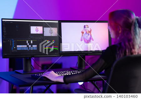 Young female video editor working on creative project with dual monitors 140103460