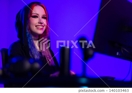 Young female streamer gaming in a modern setup with neon lighting 140103463