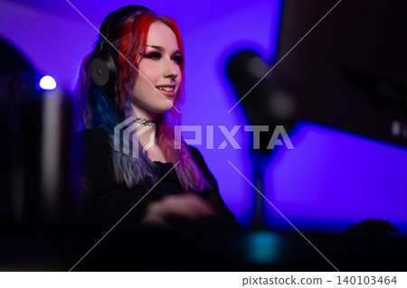 Young woman gaming or streaming in a vibrant and focused environment 140103464