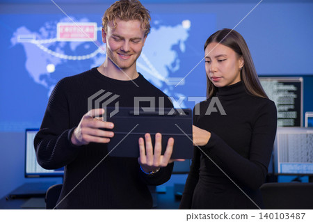 Two cybersecurity analysts collaborating in a modern SOC environment with digital maps 140103487