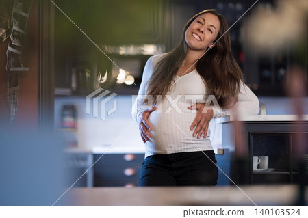 Pregnant woman smiling warmly in a modern home interior setting Pregnant woman smiling warmly in a modern home interior setting 140103524