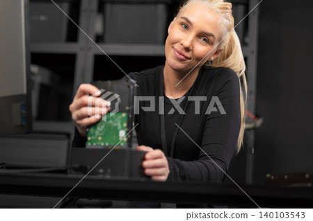 Young woman IT security technician handling storage hardware in a tech office environment Young woman IT security technician handling storage hardware in a tech office environment 140103543