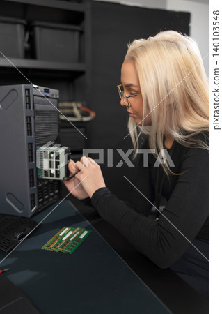 Female IT technician with blonde hair working on server hardware and RAM upgrade in data center Female IT technician with blonde hair working on server hardware and RAM upgrade in data center 140103548
