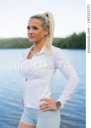Fitness enthusiast outdoors with a wearable device by a scenic lake Fitness enthusiast outdoors with a wearable device by a scenic lake 140103551