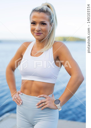 Active woman enjoying outdoor fitness with smartwatch by a scenic lake Active woman enjoying outdoor fitness with smartwatch by a scenic lake 140103554