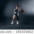 Full length of a young female professional basketball player dribbling over a black background 140103662