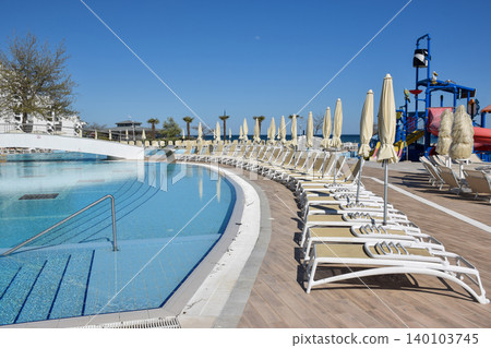Swimming pool area with sun loungers and umbrellas under clear blue sky. Bulgaria, Golden sands resort. Swimming pool area with sun loungers and umbrellas under clear blue sky. Bulgaria, Golden sands resort. 140103745