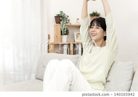 一位女士在沙發上伸展身體，讓自己放鬆。 140103942