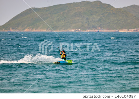 Nha Trang, Khanh Hoa - Vietnam - April 4, 2026: Kitesurfer Cutting Through Waves in Open Sea Nha Trang, Khanh Hoa - Vietnam - April 4, 2026: Kitesurfer Cutting Through Waves in Open Sea 140104087