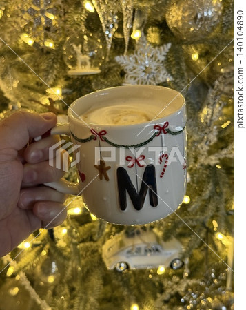 hand holding a cup of hot coffee next to Xmas tree hand holding a cup of hot coffee next to Xmas tree 140104890