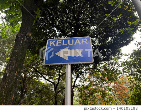 Blue keluar exit sign with left arrow in garden directional navigation Blue keluar exit sign with left arrow in garden directional navigation 140105198