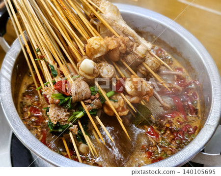 Spicy Sichuan style hot pot skewers simmering in a flavorful chili broth Spicy Sichuan style hot pot skewers simmering in a flavorful chili broth 140105695