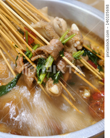 Spicy Sichuan style hot pot skewers simmering in a flavorful chili broth Spicy Sichuan style hot pot skewers simmering in a flavorful chili broth 140105698