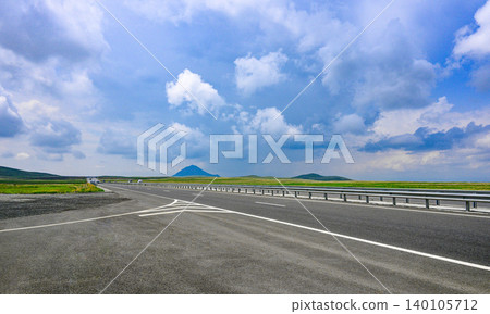 Empty asphalt road under partly cloudy sky Empty asphalt road under partly cloudy sky 140105712