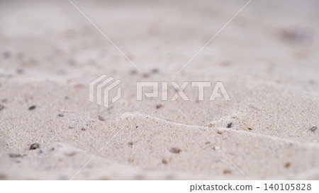 Sand patterns on beach with small stones and shells at low tide during daylight near ocean waves 140105828