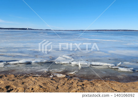 Frozen lake surface with ice shards on sandy beach Frozen lake surface with ice shards on sandy beach 140106092
