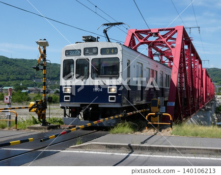 上田電氣鐵道1000系丸通姆號列車駛過上田電氣鐵道別所線上的千曲川大橋。 140106213