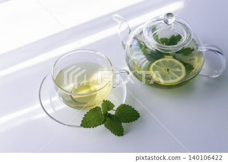 Herbal tea with lemon balm and lemon slices, served in a glass teapot. 140106422