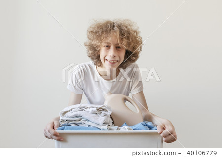 Teenager Doing Laundry With Basket Of Clean Clothes And Detergent Bottle Teenager Doing Laundry With Basket Of Clean Clothes And Detergent Bottle 140106779