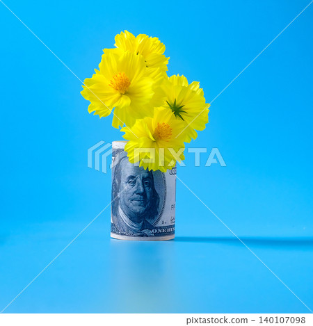 A hundred dollar bill is tightly rolled with flowers. A hundred dollar bill is tightly rolled with flowers. 140107098