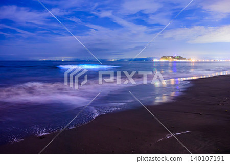 A moonlit view of Shichirigahama and Enoshima at night; a fantastical scene with bioluminescent plankton glowing blue in the sea and white clouds floating in the sky, captured with a slow shutter speed. A moonlit view of Shichirigahama and Enoshima at night; a fantastical scene with bioluminescent plankton glowing blue in the sea and white clouds floating in the sky, captured with a slow shutter speed. 140107191