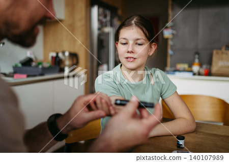 Father checking blood sugar level of diabetic teenage daughter using glucose meter. Father checking blood sugar level of diabetic teenage daughter using glucose meter. 140107989