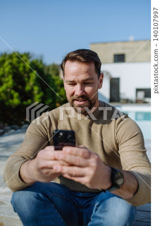 Man enjoying warm spring sunlight on face while standing outside. 140107997