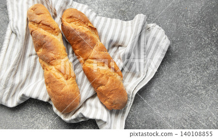 Freshly baked baguettes resting on striped kitchen towel Freshly baked baguettes resting on striped kitchen towel 140108855