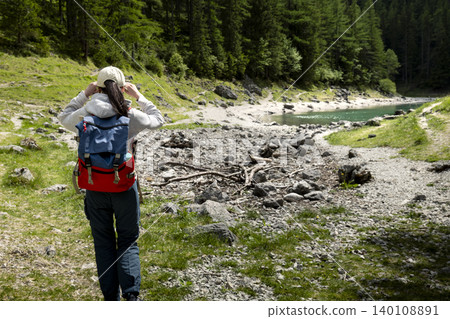 Woman hiker with backpack walking on a mountain path in the Austrian Alps, highlighting exploring remote mountain landscapes Woman hiker with backpack walking on a mountain path in the Austrian Alps, highlighting exploring remote mountain landscapes 140108891