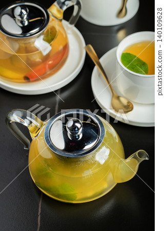 Fruit tea with mango and mint in a glass teapot on the table 140109628