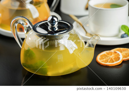 Fruit tea with mango and mint in a glass teapot on the table Fruit tea with mango and mint in a glass teapot on the table 140109630