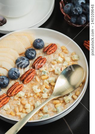 Oatmeal. Bowl of oatmeal porridge with blackberry, bananas and chia seeds on gray concrete old table background. Top view in flat lay style. Natural ingredients. Hot healthy breakfast and diet food 140109648