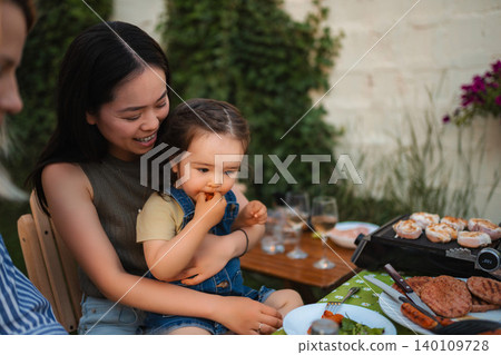 Happy multi-ethnic family enjoying outdoor eating and barbecue Happy multi-ethnic family enjoying outdoor eating and barbecue 140109728