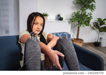 Bored young adult girl sitting on sofa holding remote control Bored young adult girl sitting on sofa holding remote control 140109779