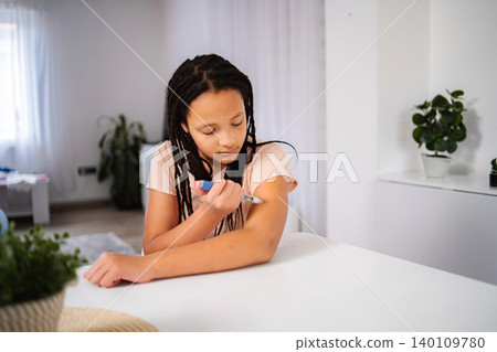 Young girl managing diabetes injecting insulin in arm 140109780