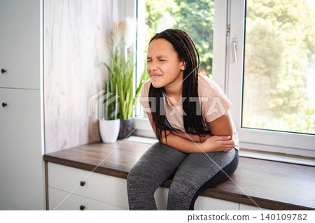 Young girl having stomach ache and abdominal pain indoors Young girl having stomach ache and abdominal pain indoors 140109782