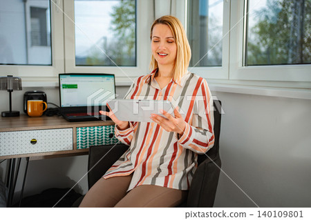 Woman smiling using digital tablet working from home office Woman smiling using digital tablet working from home office 140109801