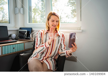 Woman waving during video call, working from home Woman waving during video call, working from home 140109904