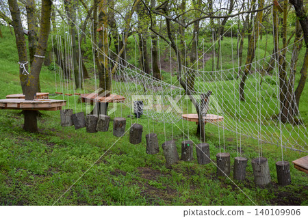 Fun Outdoor Adventure Ropes Course with Rope Net and Tree Stump Obstacles in Forest 140109906
