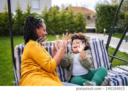 Mother and son playing games on swing 140109915
